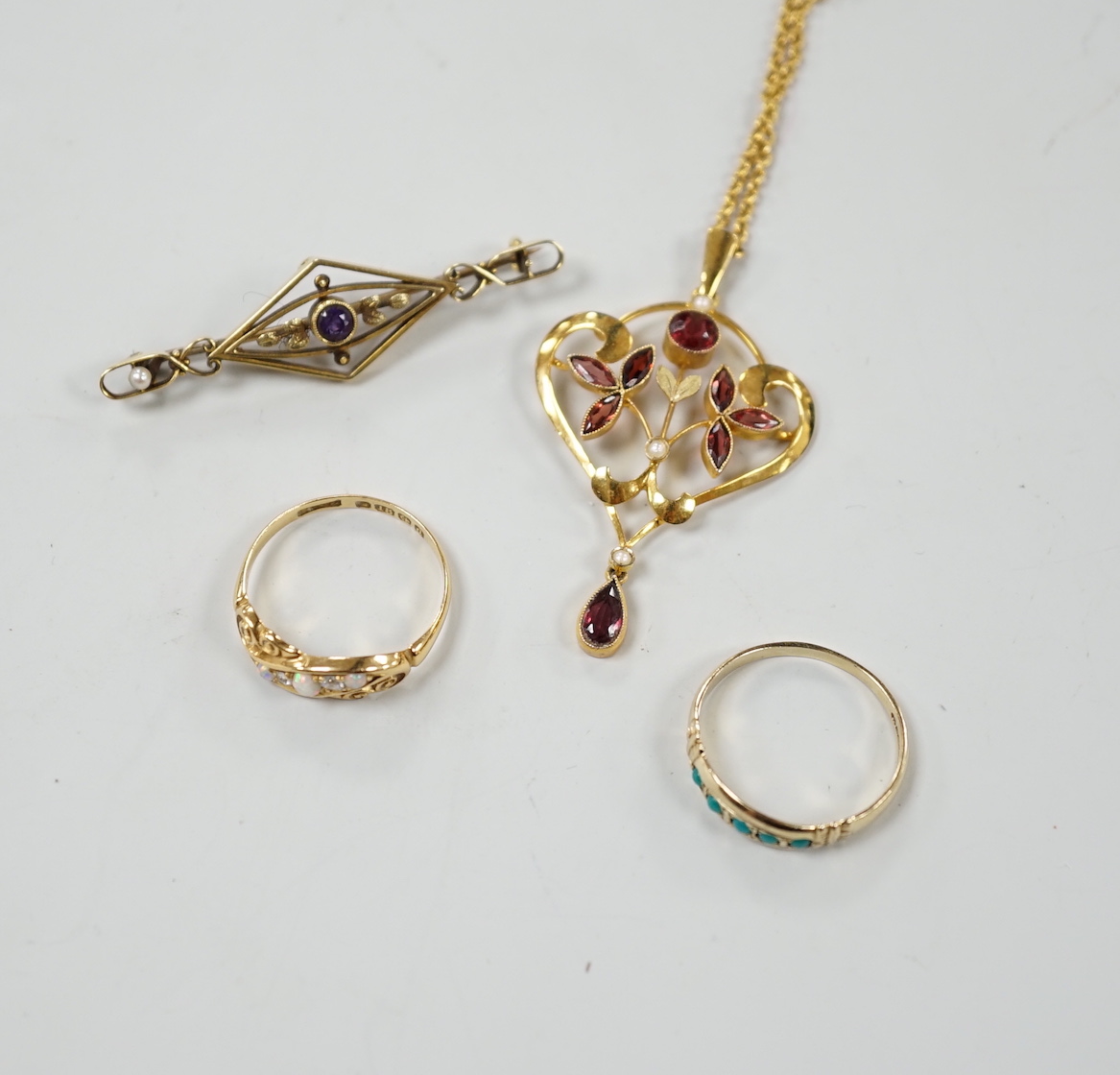 An early 20th century 9ct, garnet and seed pearl set drop pendant, overall 45mm, on a yellow metal chain, a 15ct and gem set bar brooch and an 18ct, opal and diamond ring and a 9ct and gem set ring.